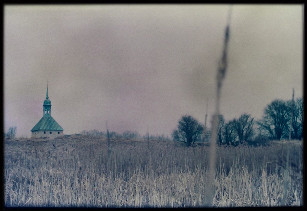 Color picture of a field with an old building at the end