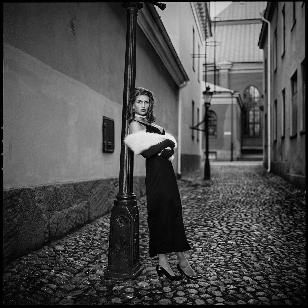 Retro black and white image of a lady leaning against a street light